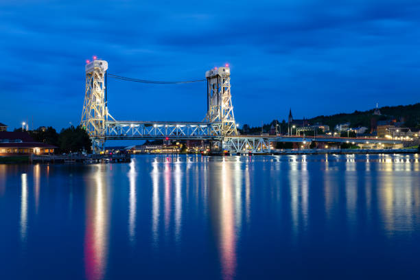 Historic lift bridge connecting Houghton and Hancock in the Upper Peninsula of Michigan.  It is the world's widest and heaviest double decker vertical lift bridge.  Photographed at night with plenty of detail, reflections, star bursts, and copy space.