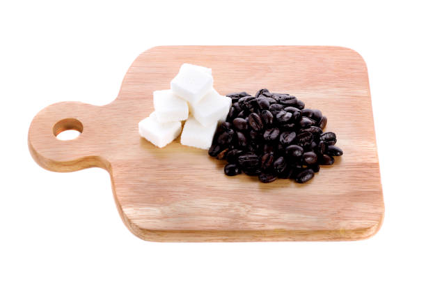 Flat lay view of hand pouring sugar into cup of black coffee on white background
