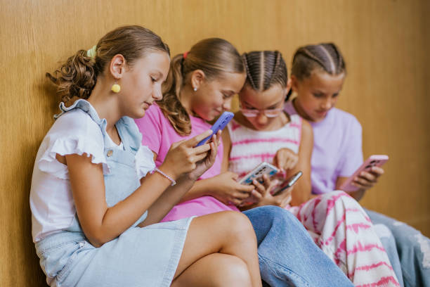 istock Students interact with mobile phones during break time in their school hallway while sitting together on the floor 2173227036