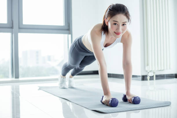 istock Young woman doing plank position with dumbbells 2173227152