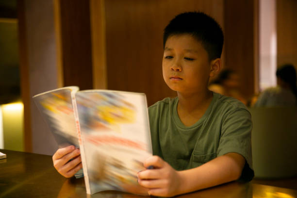 A little boy is reading books seriously in the library