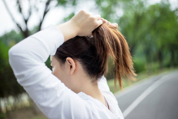 Woman tying hair in ponytail getting ready for run.