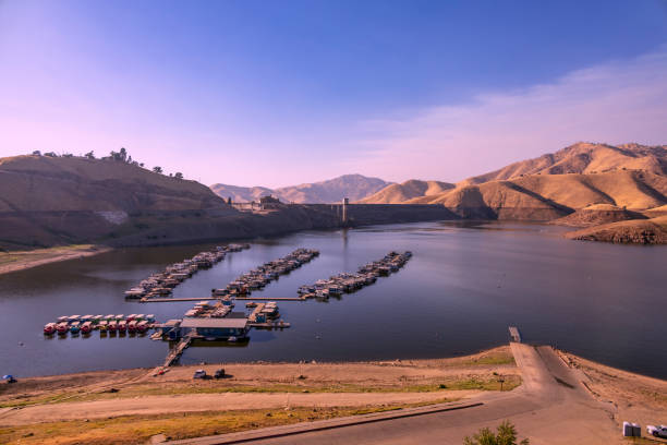 Scenic view of Kaweah Marina, near Sequoia National Park, showing houseboats on calm waters with dry hills in the background, captured at sunset.