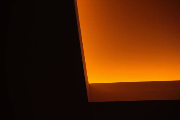 Interior of a tunnel or passageway with a curved ceiling made of reflective, metallic panels. Ceiling is lined with fluorescent lights that create a modern and futuristic appearance