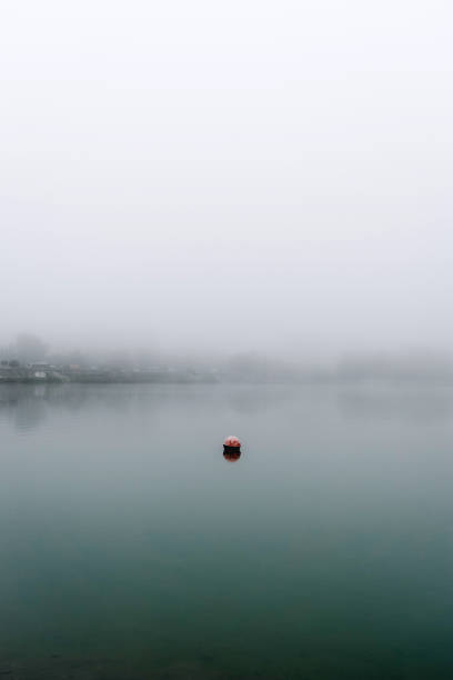 istock Single Red Buoy Floating on Foggy Lake 2173283014