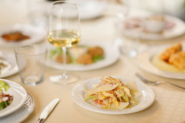 Close-up of assorted Chinese appetizers beautifully arranged on a white ceramic plate with garnish and flowers during a restaurant banquet.