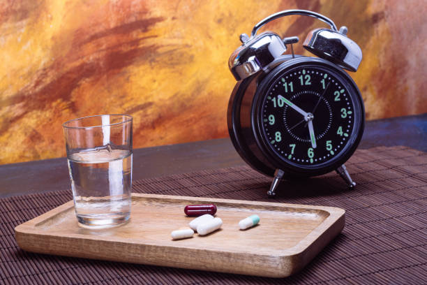 istock Assorted pills on tray with water and alarm clock on table 2173288581