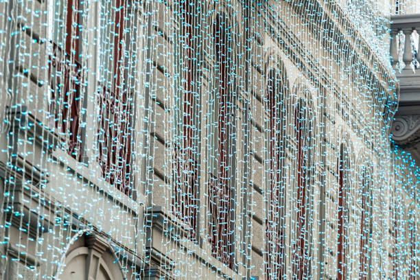 Blue christmas lights cascade down a building's exterior, creating a sparkling string of illumination