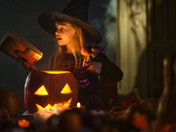 istock Cute little girl casting spells on Jack O' Lantern on Halloween. 2173300409