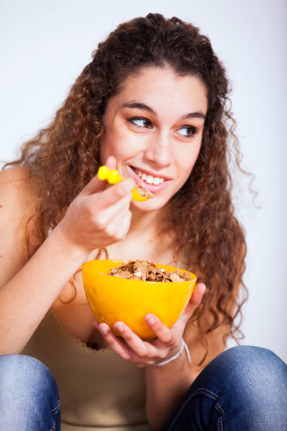 Young woman eating cereals in her room