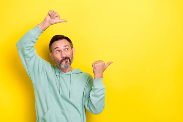 istock Photo of thoughtful positive optimistic guy dressed mint sweatshirt look indicating empty space isolated on yellow color background 2173326902