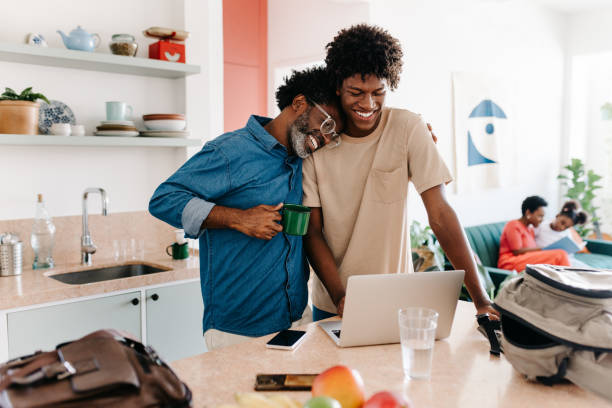 Father and son using a laptop during their daily morning routine in the kitchen