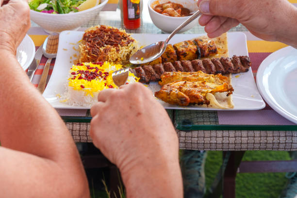 Hands with spoon and fork getting ready for Oman traditional food in one portion, chicken, mutton, fish and rice.