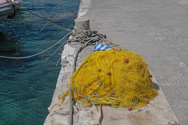 Yellow-coloured fishing nets in heaps on the beach.