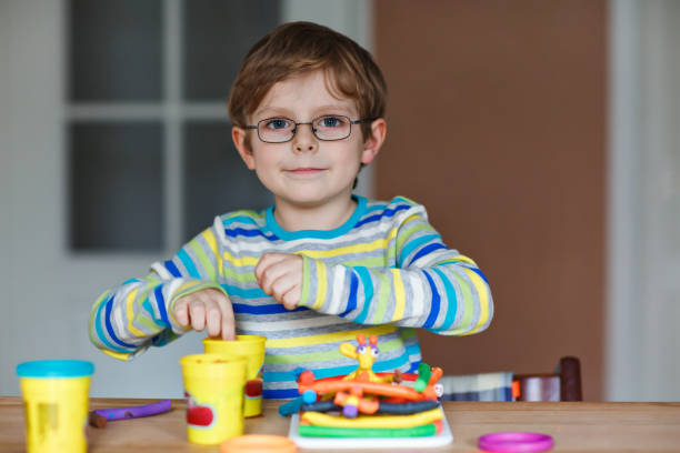 istock Smiling preschool kid boy having fun with dough, colorful modeling compound clay. Creative leisure with children. during corona virus quarantine staying at home. Shelter in place, lockdown concept, 2173334544