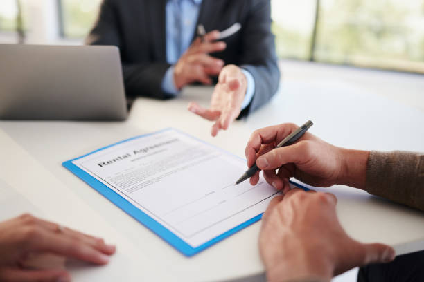 Close up of unrecognizable man signing a contract during a meeting with his real estate agent in the office.