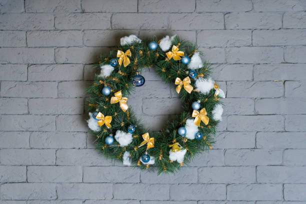 istock A beautifully crafted Christmas wreath is hanging on a white brick wall 2173342098