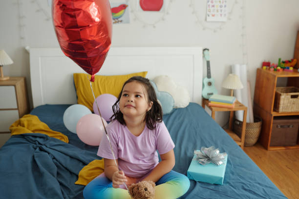 istock Girl Sitting With Balloon On Her Bed 2173343536