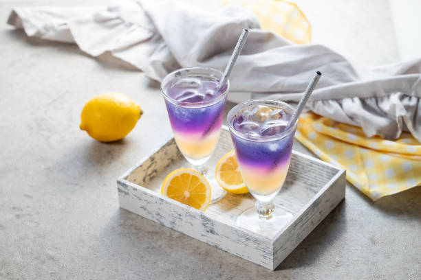 Lemonade with blue and violet butterfly pea flower tea on light gray background with copy space