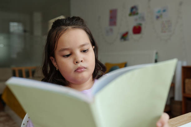 istock Schoolgirl Reading Book At Home 2173344859