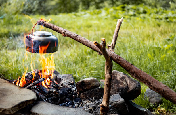 istock Making tea over an open fire in the forest. The kettle is hanging on a stick on the fire. 2173345211