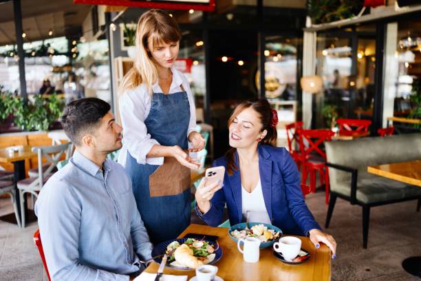 istock Woman asking for help from waitress while holding her phone 2173347370