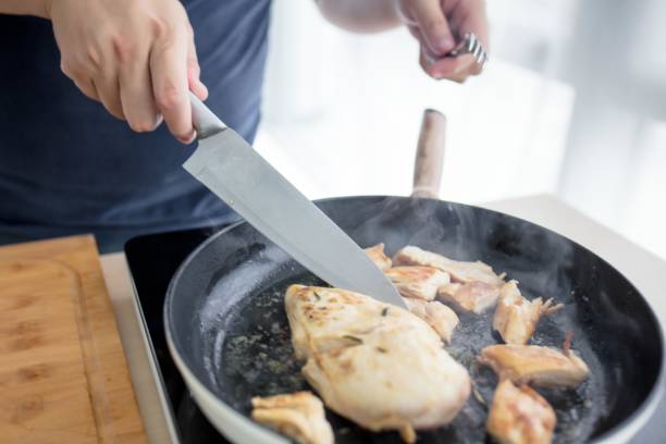 istock A man cooking chicken in a frying pan 2173349694