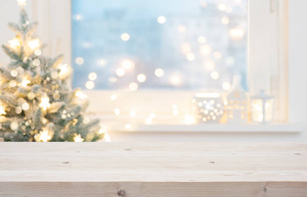 Blur Christmas tree and decorated window interior background with wooden table top for product display in front