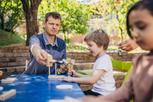 istock Man teaching kids woodworking in outdoor setting 2173359730