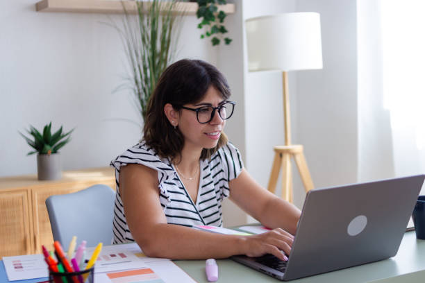 istock Young woman working from home on laptop is typing and smiling 2173362976