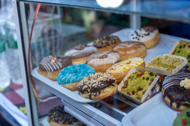 The image features a variety of colorful donuts with different toppings, displayed in a glass case.