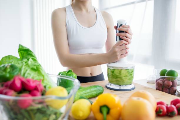 istock Woman making healthy green smoothie with blender in kitchen 2173371181