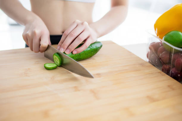 Closeup on young woman slicing vegetables