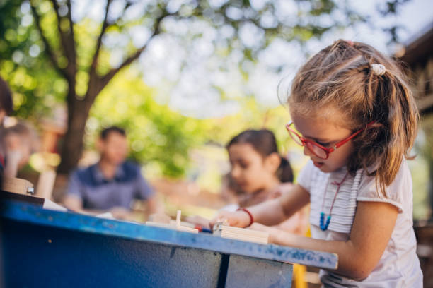 istock Girl immersed in creative craft work at blue outdoor table. 2173378001