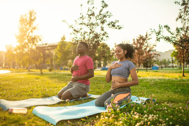 istock Young couple practicing yoga in a summer park, doing breathing exercise 2173382927