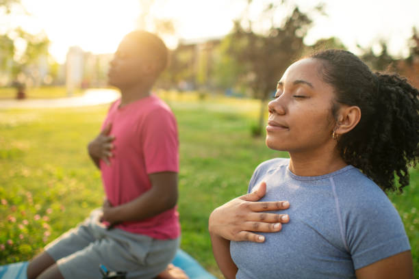 Young couple practicing yoga in a summer park, doing breathing exercise