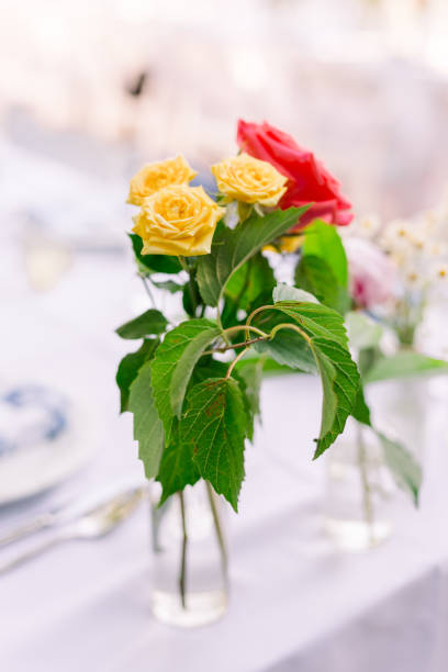 istock Freshly cut yellow and red flowers in a vase on a white tablecloth table. 2173386355