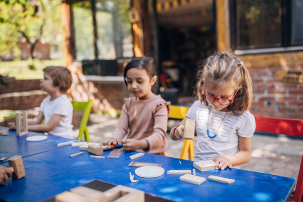 istock Children crafting at table outdoors with wooden blocks 2173388828