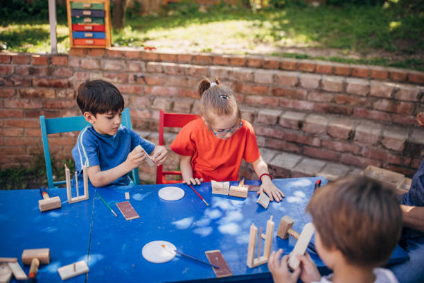 istock Children focused on outdoor crafting projects at table. 2173395055