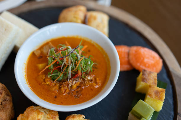 istock Nyonya red curry in white bowl placed on a plate, surrounded by various kuih. Malaysia traditional food. 2173401598