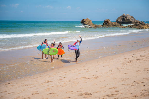 Bidart, France - 07.11.2024: A group of surfers with surfboards  in their hands coming out of the ocean.