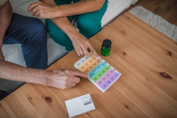istock An unrecognizable female nurse sits next to an elderly patient helping him arrange supplements in a plastic pill box 2173409339