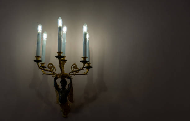 istock Bronze sconce with electric candles in sconces against a dark wall. 2173418900