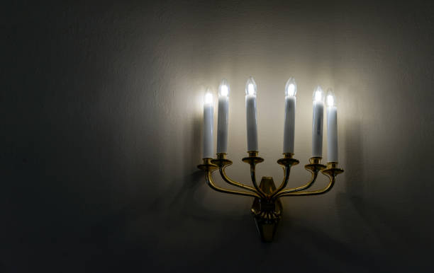 istock Bronze sconce with electric candles in sconces against a dark wall. 2173418921