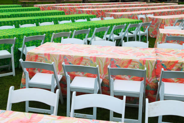Colorful table and folding chair rows lined up in preparation for a big outdoor dinner event on green lawn
