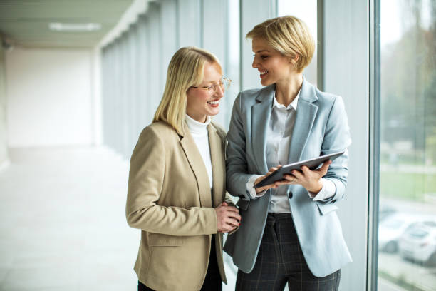 istock Happy businesswomen standing and talking while using digital tablet 2173431171