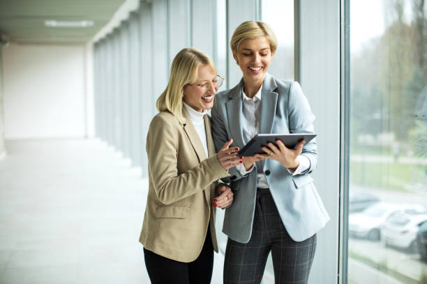 istock Happy businesswomen standing and talking while using digital tablet 2173431177
