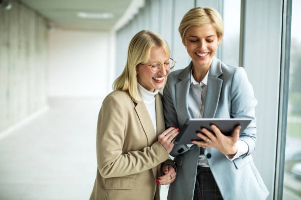 istock Happy businesswomen standing and talking while using digital tablet 2173431180