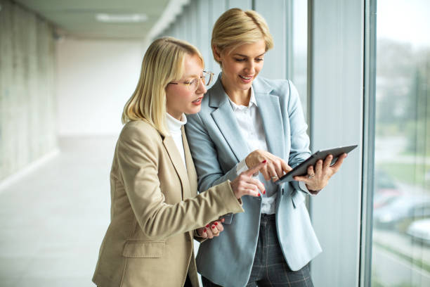 istock Happy businesswomen standing and talking while using digital tablet 2173431186