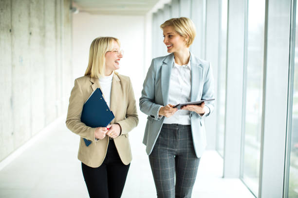istock Happy businesswomen standing and talking while using digital tablet 2173431247